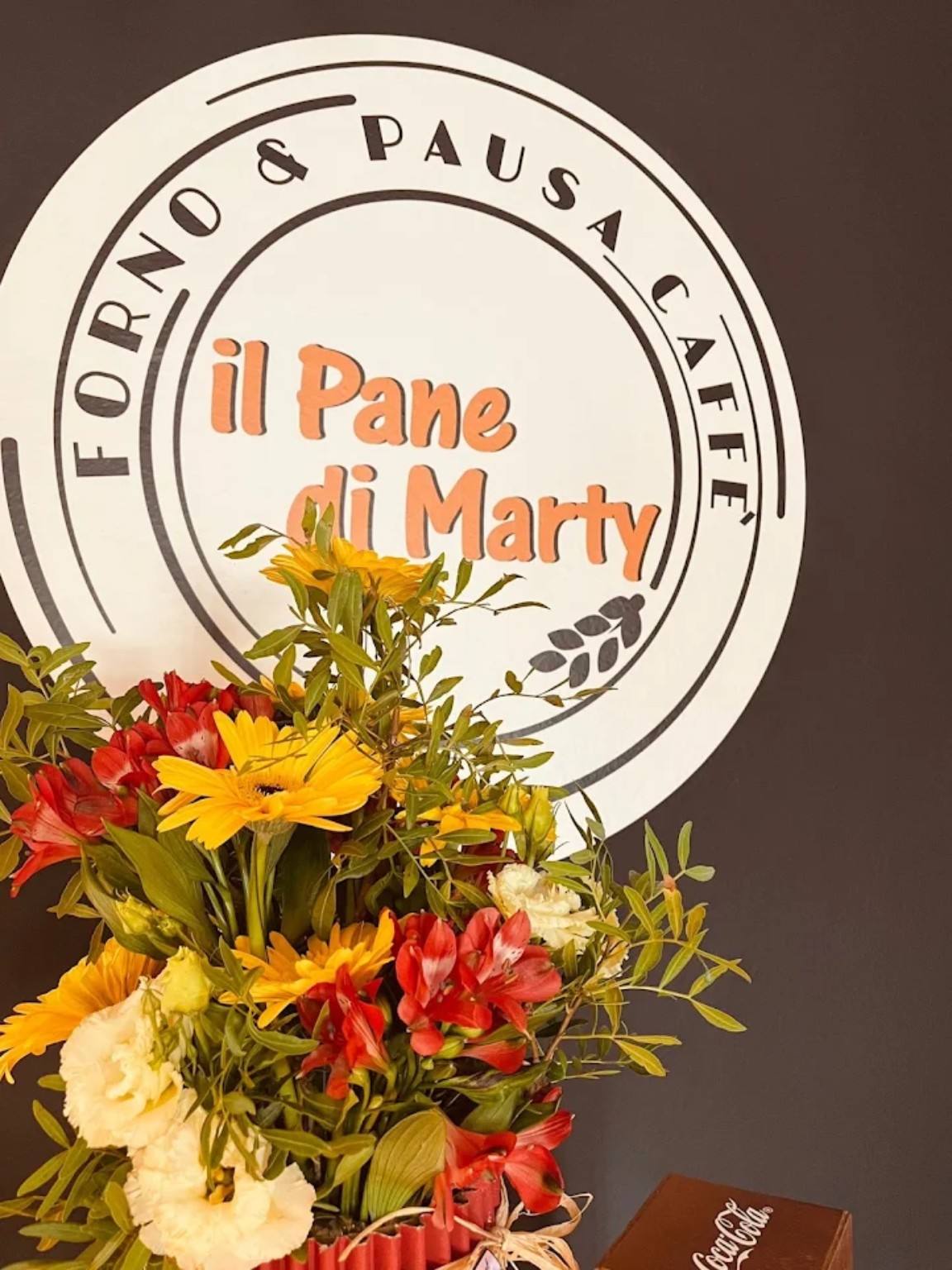 Il logo originale Il Pane di Marty con un mazzo di fiori all'interno del locale