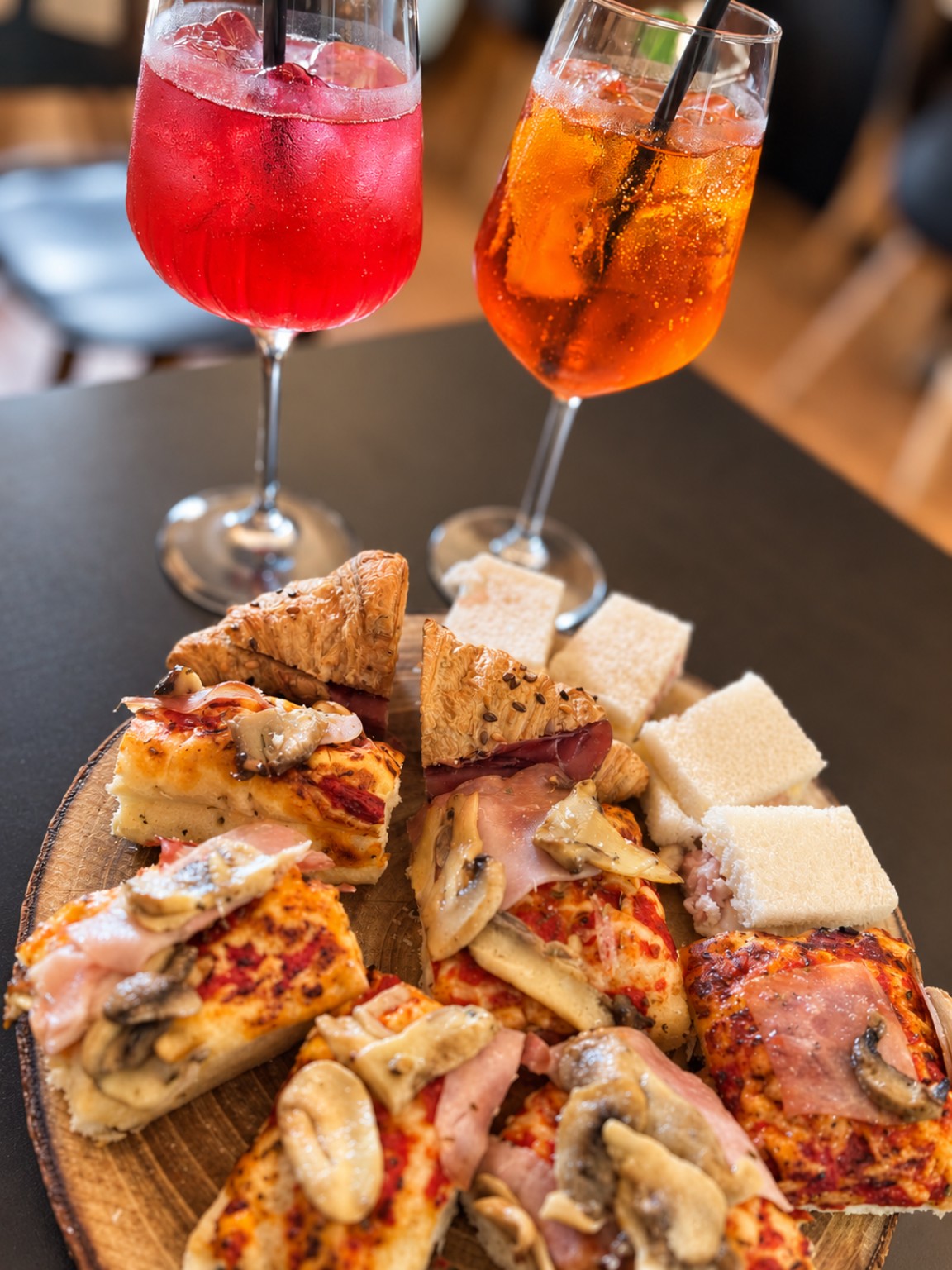 Aperitivo al Pane di Marty: due bevande colorate e un tagliere con focaccia, sfoglie e tramezzini