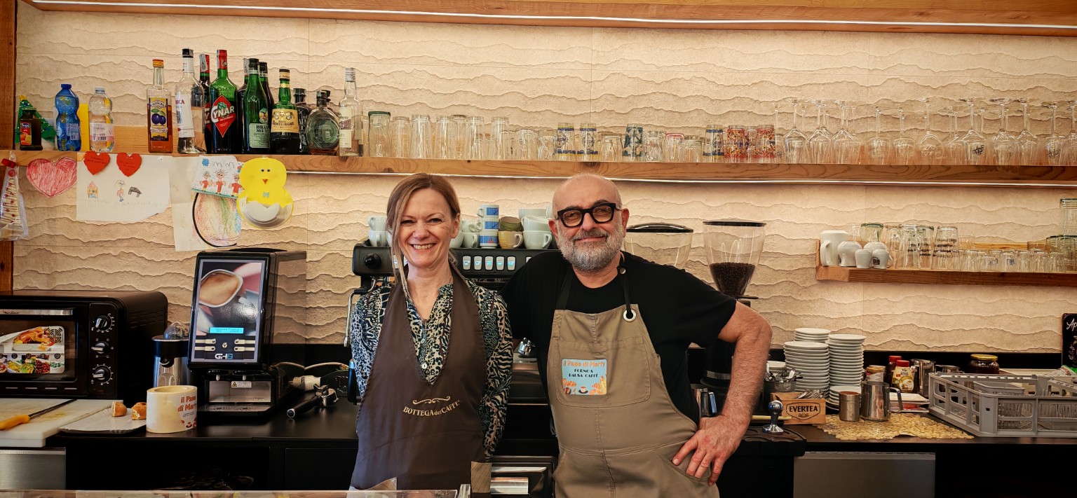 Martina e Giovanni sorridenti dietro il banco del locale
