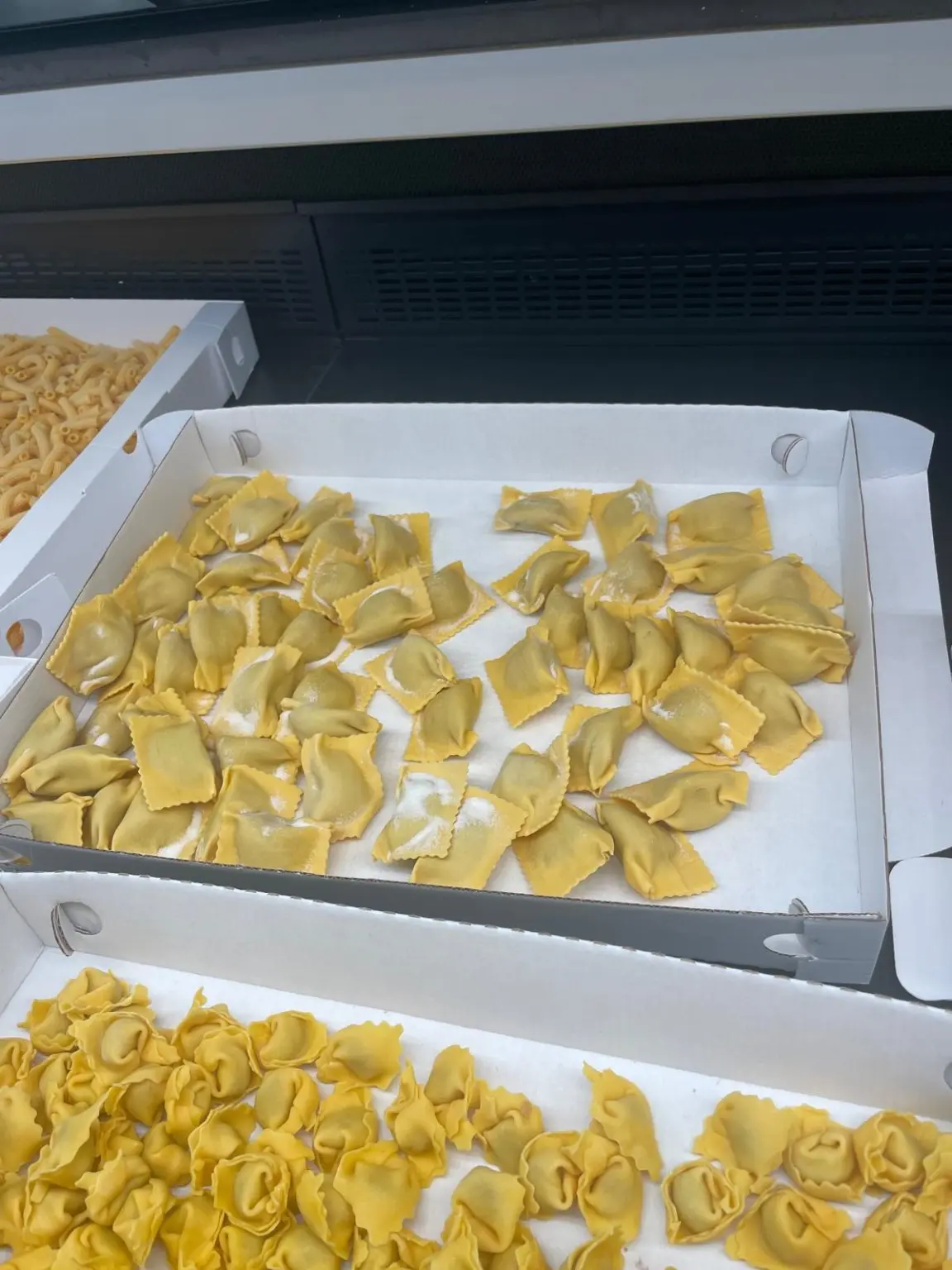 Ravioli e tortellini all'uovo in scatole bianche nel banco del locale